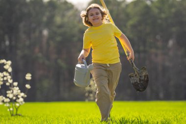 Bahçede çalışan bir çocuk. Bahçede yetişen ağaç ve bakım bitkisi. Bahçıvanlık sezonu. Bitki yetiştiren bir çocuk. Bahçe işleri. Çocuk bahçede meyve ağacı suluyor. Çocuk dikme ağacı. Bahçede bahar