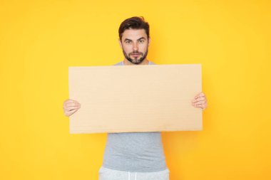 Stüdyo arka planında boş tahtası olan bir adam. Kopya alanı olan boş tabela. Reklam konsepti. Fotokopi alanı olan reklam panosu, boş kopya alanı. Boş tabela, kopyalama alanı olan pano