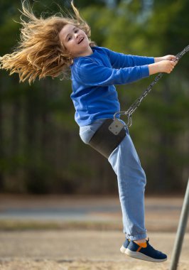 Çocuk salıncakta eğleniyor. Çocuk bahçesinde mutlu bir çocuk. Havada sallanan kaygısız çocuk. Mutlu çocuklar dışarıda oynuyor. Sarışın çocuk heyecandan titriyor. Dışarıdaki oyuncu çocuk. Komik çocuk suratı