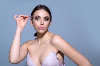 Koyu kaşlı güzel bir kadın kaş fırçası tutuyor. Kaş kaplaması. Güzellik prosedürlerini uygula. Kaş ve kaş çizgisi, kaş çizgisi.