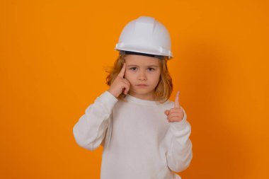 Kasklı, inşaatçı üniformalı bir çocuk. Kasketli genç mimarın stüdyo portresi. Becerikli çocuk. Çocuk inşaat işçisi. Çocuk müteahhit. Tamirci kıyafeti giymiş çocuk.