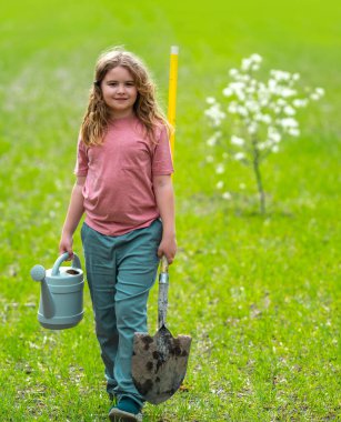 Çocuk çayırda ağaç dikiyor. Çocuklar meyve ağacı gibi büyür. Kürekli çocuk bahçıvan. Çocuk meyve bahçesinde çiçek açan ağaçlarla çalışıyor. Çocuklar arka bahçeye ağaç dikiyorlar. Ağaçlarla ilgilenen genç çiftçi