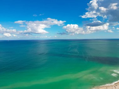 Bulutlu mavi gökyüzünde deniz. Miami 'de deniz kıyısı, hava manzaralı. Deniz sahili. Deniz iskelesi. Güzellik kıyısı