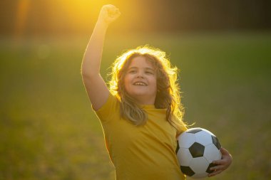 Çocuk futbol oynuyor. Çocuk çimlerde futbol topunu tekmeliyor. Futbol topuyla koşan bir çocuk. Futboldan zevk alan oyuncu çocuklar. Çocuklar futbol maçı. Futbol oynayan çocuk topa vuruyor.