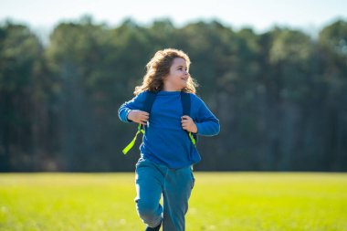 Çocuk sahada koşuyor. Dışarı koşan mutlu çocuk. Çocuk doğada zıplıyor ve koşuyor. Çayırda koşan bir çocuk. Aktif çocuklar için yaz eğlencesi. Neşeli çocuk özgürlüğü. Doğada özgür çocukluk