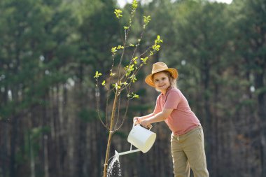 Bahar tarlasında çocuk dikme ağacı. Sulama kovası ve kürekle ekmek. Bahçe çiftliğinde ağaç yetiştiren çocuk. Çocuk işi