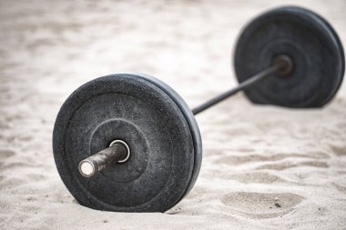 Halter spor ekipmanları. Spor geçmişi. Yaz sporu için kumda halter. Kum arka planda halter. Spor salonunda halterle idman yapıyorum. Spor afişi