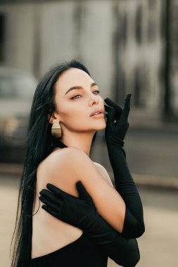 Sokakta poz veren güzel esmer kadın portresi. Moda dünyasından genç ve güzel bir kızın yakın plan kadın portresi, yaz sokak modası. Şık bir açık hava kadınının yüksek moda yakın plan portresi