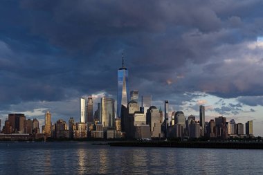 New York şehri. New York şehir manzarası. New York 'taki Lower Manhattan ve One World Trade Center. Manhattan 'ın gökdelenleri New York körfezinin dalgalanan sularının yanında mavi gökyüzüne karşı. New York gökdelenleri