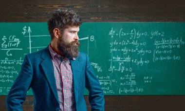 Öğretmen sınıfta matematiği açıklıyor. Profesör, matematik dersinde. Öğretmen matematik formülü yazıyor. Sakallı öğretmen. Profesör sınıfta ders veriyor. Öğretmen matematiği açıklıyor. Öğretmenler Günü