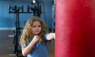 Eğitimdeki boksör çocuk. Çocuk boksörü egzersizi. Sportif çocuk boks torbasına vuruyor. Çocuk kickboks ve boks çalışıyor. Aktif çocuk dövüşçüsü portresi. Spor salonunda boks egzersizi. Çocuklar için spor ve güç