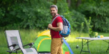 Turistler doğada kamp yapmayı seviyor. Doğaya yaz gezisi. Orman kampında dinlenen adam. Kamp gezisi. Yürüyüşten sonra çadırın yanında dinleniyor. Barışçıl bir kamp alanında özgürlük tatili. Yazın piknikteki adam