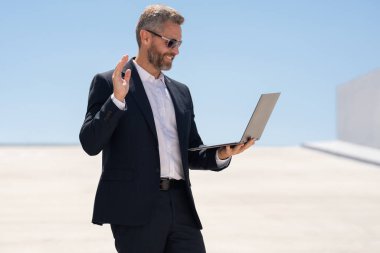 İş adamı dışarıda dizüstü bilgisayar kullanıyor. Dizüstü bilgisayar kullanan başarılı bir adam. Dizüstü bilgisayarı olan kendine güvenen bir iş adamı. İnternette iş. İş adamı laptoptaki verileri kontrol ediyor. Takım elbiseli iş adamı internette çalışıyor.