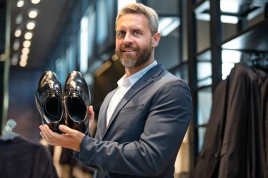 Moda mağazasındaki müşteri farklı ayakkabı stillerini değerlendirir. İş adamı kendine güvenerek şık ayakkabıları bir ayakkabı mağazasında seçer. Resmi görünmek için klasik deri ayakkabılar. Resmi ayakkabılar. Deri ayakkabılar.