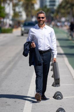 İş adamı işe yürüyerek gider. İspanyol işadamı sokakta güvenle yürüyor. Ofis çalışanı ofise gidiyor. Orta yaşlı iş adamı şehirde yürüyor. Yazlık kıyafetli bir iş adamı.