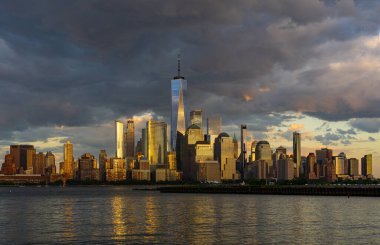 New York şehri. New York şehir manzarası. New York 'taki Lower Manhattan ve One World Trade Center. Manhattan 'ın gökdelenleri New York körfezinin dalgalanan sularının yanında mavi gökyüzüne karşı. New York gökdelenleri