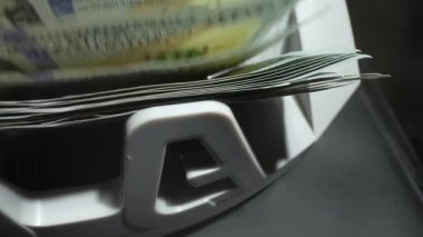 Para saymak. Para sayma makinesini kapat ve dolarları say. Makine sayacı 100 dolarlık banknotları yavaş çekimde hesaplar. Kapatma para sayma makinesi dolar banknotlarını sayıyor