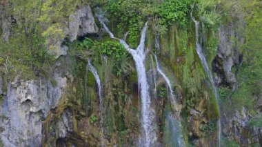 Plitvice Gölleri. Dağlarda şelale. Nefes kesici bir manzarada şelale hareketi. Göl düşen suyun altında parıldıyor. Yeşil vadideki şelalelerin güzelliği. Plitvice Ulusal Parkı