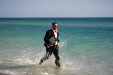 Yaz işi. Yazın deniz sahilinde serbest koşucu. Dalgıç kıyafetli bir iş adamı deniz suyuna atlar. Çılgın bir yaz tatili. Kumsalda dizüstü bilgisayarı olan komik bir iş adamı. Sıcak yaz