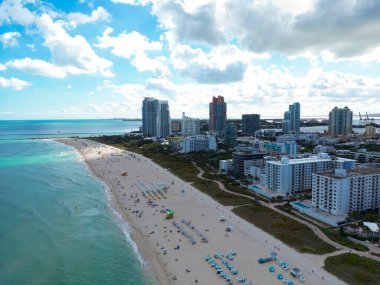 Miami 'de kumsalda güneşli yataklı, okyanus dalgalı bir plaj. Muhteşem manzaralı Miami Beach cenneti. Güney Sahili Miami cankurtaranı. Miami 'de huzurlu bir deniz kenarı inzivası. Kıyı gevşemesi