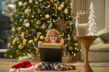 Evdeki noel ağacının yanındaki çocuk.