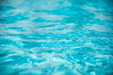 Yüzme havuzundaki mavi suyun arka planında güneş yansıması, havuzda dalgalı su dalgaları. Temiz su arkaplanı
