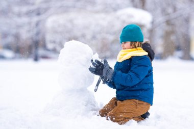 Mutlu Çocuk kışın kardan adam için kartopu yapıyor. Çocuk karda oynuyor. Açık havada aktif kış oyunları. Çocuk karla oynarken eğleniyor. Çocuklar için açık havada kış tatili. Güneşli kış gününde çocuk oyunu