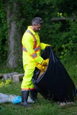 Dışarıdaki çöpleri toplayan gönüllü adam. Ekoloji konsepti. Çevre kirliliği. Dünya Günü. Çöp tenekelerini geri dönüşümle temizleyin. Doğa temizliği. Çevre plastik kirliliği