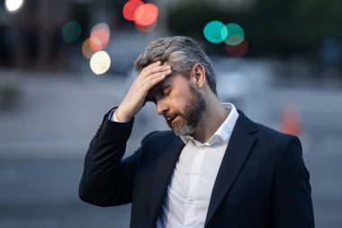 Dışarıda baş ağrısı çeken yorgun bir iş adamı. Migren ağrısını dindiren bir adam. Finansal sorunlar ve stres. İş krizi ve iflas kavramı. İş adamı endişeli ve stresli