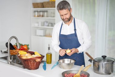 Mutfakta sebze doğruyor. Önlüklü şef modern mutfakta sağlıklı yemek hazırlıyor. Mutfakta sebzeli yemek. Aşçı evde sebzelerle kahvaltı hazırlar.