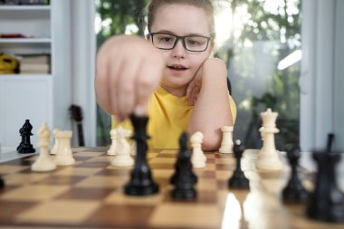 Çocuk evde satranç taşlarına konsantre oluyor. Satranç tahtasında çocuk planlama stratejisi. Satranç tahtasındaki çocuk düşüncesi. Satrançta çocuk zaferi. Satranç oynayan düşünceli bir çocuk. Evde genç bir satranç oyuncusu
