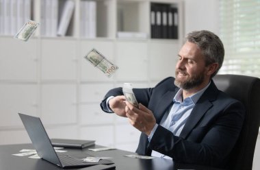 Takım elbiseli bir işadamı ofise para atıyor, heyecanlı görünüyor. Freelancer dolar fırlatıyor. Yakışıklı bir girişimci para saçar. Bir satıcı para fırlatır Başarı finansal anlaşmalar konsepti