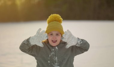Parkta kar topu savaşı. Çocuk kar yağışında neşeyle oynuyor. Kış çocukları portresi. Mutlu çocuk yüzünde kar taneleri. Soğuk kışın çocukları. Kış eğlenceli geçiyor. Karlı havada bir çocuk. Kış tatili