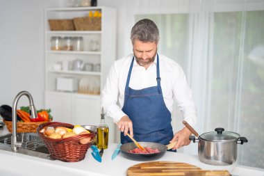 Şef mutfakta sebze doğruyor. Önlüklü bir adam hammaddeyle sağlıklı bir yemek hazırlar. Sebzeli yemek. Akşam yemeği için taze sebzeli şef. Aşçı sebzelerle kahvaltı hazırlar.