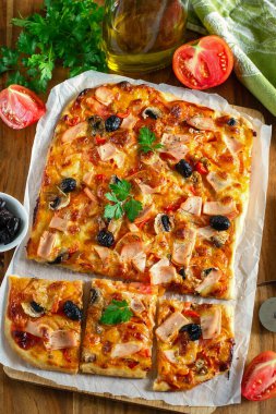 Jambon, domates, peynir ve zeytinli ev yapımı dikdörtgen pizza.