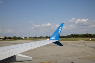 BUCHAREST, ROMANIA - CRCA 2022: Uçağın kanadında Fly Dubai 'nin yakın görüş logosu. Uçak penceresinden Otopeni Havaalanı 'na kalkışa hazırlanırken görüntüyü alın. Seyahat ve ulaşım kavramı.