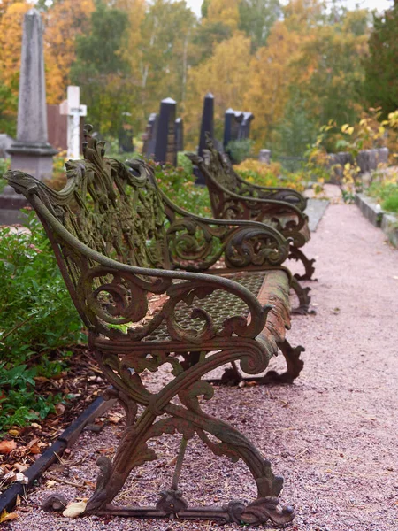 Old oddly shaped metal bench in European cemetery: Finland, Helsinki, Hietaniemi, autumn.