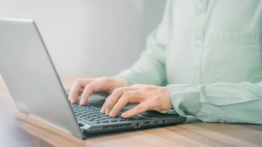 Bilgisayarda çalışan ve daktilo kullanan genç bir adamın yakın plan görüntüsü. Odadaki ahşap masada..