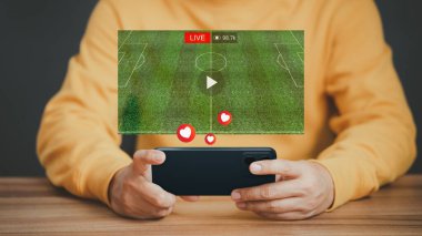 Akıllı telefon ya da cep telefonu kullanan bir adam sanal ekranda canlı futbol izlemekte, internette video aramakta, içerik kavramını internette araştırmaktadır..
