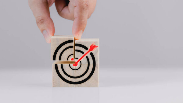 Hand put a goal icon on wooden cube block on wood table. Business growth and goal in next year concept
