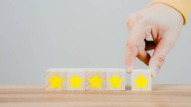 Customer's hand selects a star icon on a wooden cube block with 5 Star Satisfaction. Best great business services rate the customer experience. Satisfaction Survey Concept.