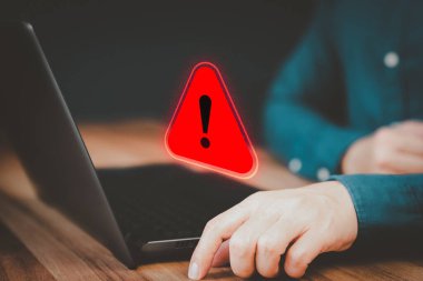 Adult man using a computer laptop with triangle caution warning sign for notification error. Concept technology of computer virus detected, personal data protection, network security and maintenance.