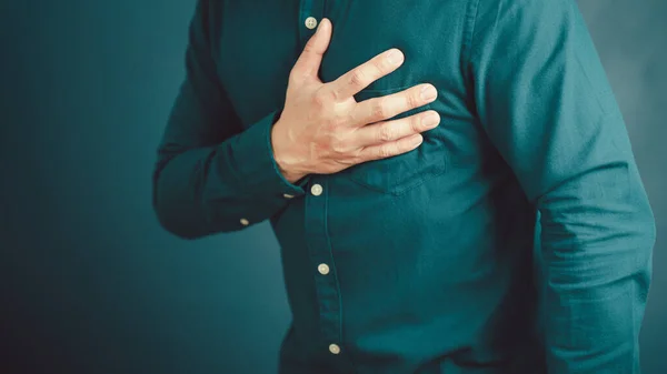 Adult man suffering from chest pain, Hand pressing on chest with painful expression, Severe heartache, Having heart attack.