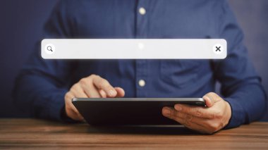 Ofisteki masada tabletle çalışan yetişkin bir adam. Boş arama çubuğu ile internet veri bilgileri taranıyor. Arama motoru optimizasyonu SEO ağ konsepti.