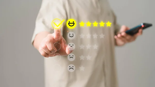 Man touching the virtual screen on the happy smiley face icon and five star to assessment satisfaction in service. Rating very impressed. Customer service, testimonial and satisfaction concept.