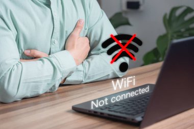 Yetişkin bir adam ofisteki kablosuz internete bağlanmak için bilgisayar kullanıyor ama kablosuz bağlantı yok. Dijital iş veri formu web sitesini yükleyip güncellemek için bekliyor. Wi-Fi 'ye bağlanma teknolojisi.