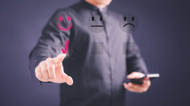 Müşteri, servisteki memnuniyeti değerlendirmek için gülen surat ikonundaki sanal ekrana dokunuyor. Derecelendirme çok etkileyici. Müşteri hizmetleri beyan ve tatmin kavramı.