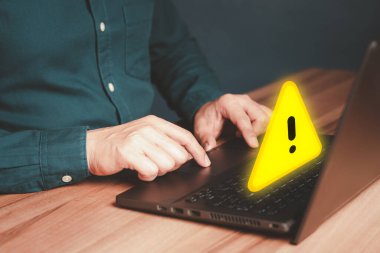 Bilgisayar virüsü teknolojisi tespit edildi, kişisel veri koruması, ağ güvenliği ve bakımı. Uyarı hatası için üçgen uyarı işareti olan bir bilgisayar dizüstü bilgisayar kullanan bir adam.
