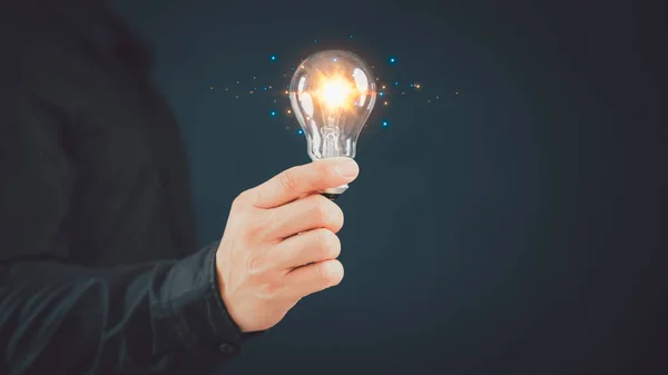 Man hand holding illuminated light bulb, creative with glowing light bulb. Inspiration concept of learning, new knowledge and sustainable business development. Innovation and inspiration idea.