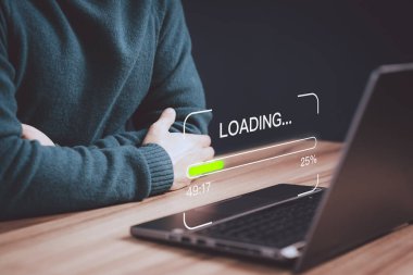 Genç adam yazılım indirmek ve güncellemek için dizüstü bilgisayar kullanıyor ve dijital dosya veri formu web sitesini yüklemeyi bekliyor, çok yavaş bir internet formu wifi. Yükleme simgesinin yüklenmesini bekleme kavramı.